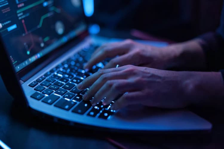 Um close-up de um teclado de laptop com as mãos digitando, focando na ação de escrever.